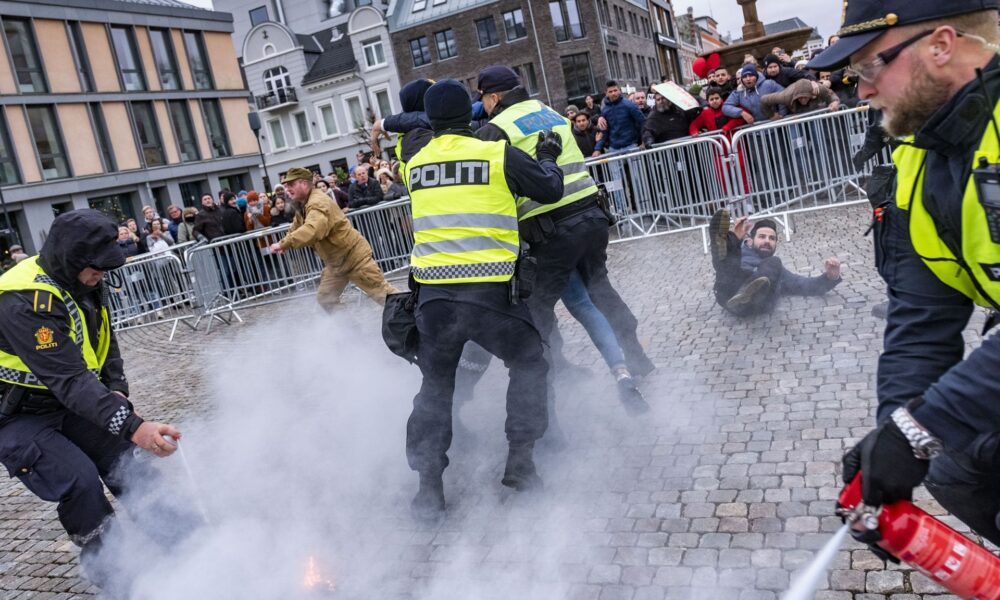 Politiet grep inn da SIAN-leder Lars Thorsen (i beige klær) satte fyr på Koranen under en markering i Kristiansand.